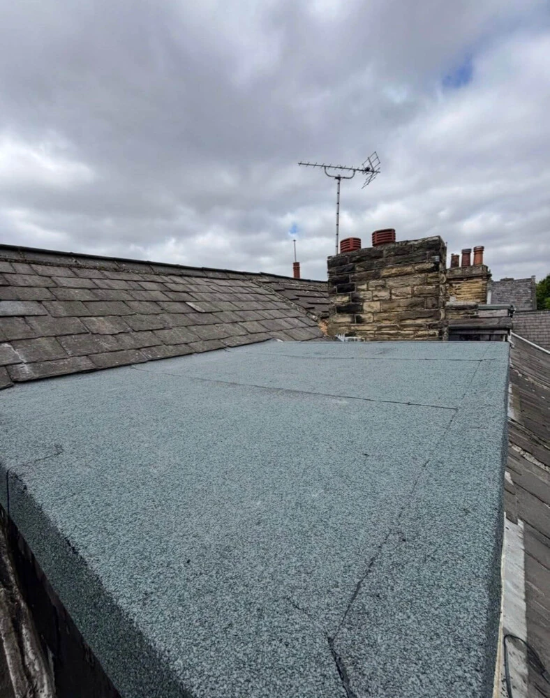 Large flat roof replacement with chimney and aerial overlooking neighbouring roofs