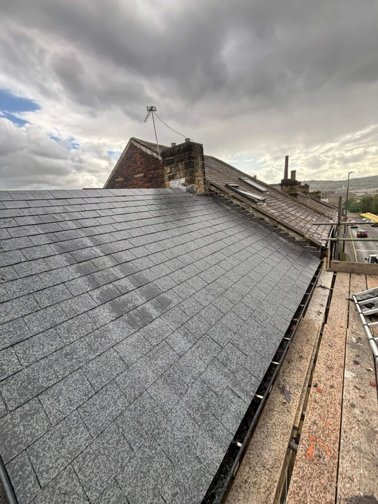 Newly re-slated pitched roof viewed from the ridge with scaffolding at the eaves