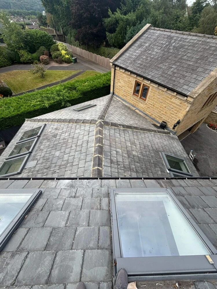 Slate roof with two large roof windows fitted beside a stone gable