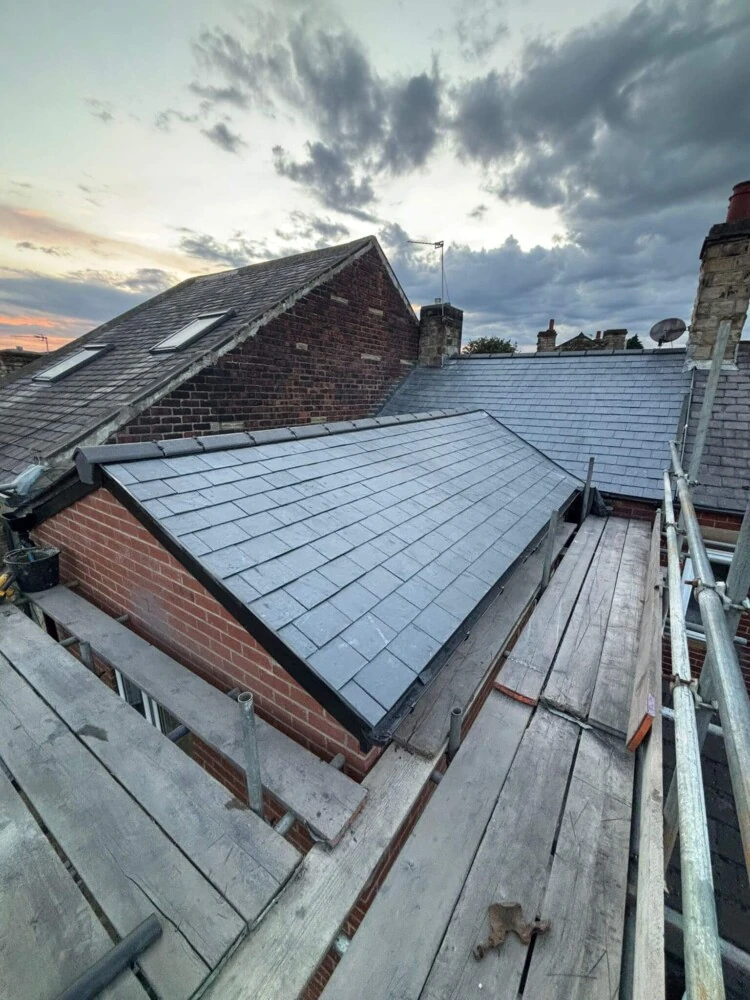 Newly slated roof on a brick extension with scaffolding tower at dusk