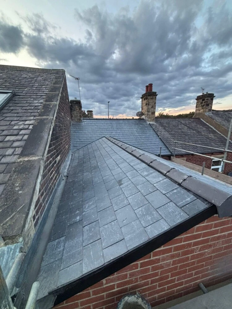 New slate roof against a red brick gable end wall